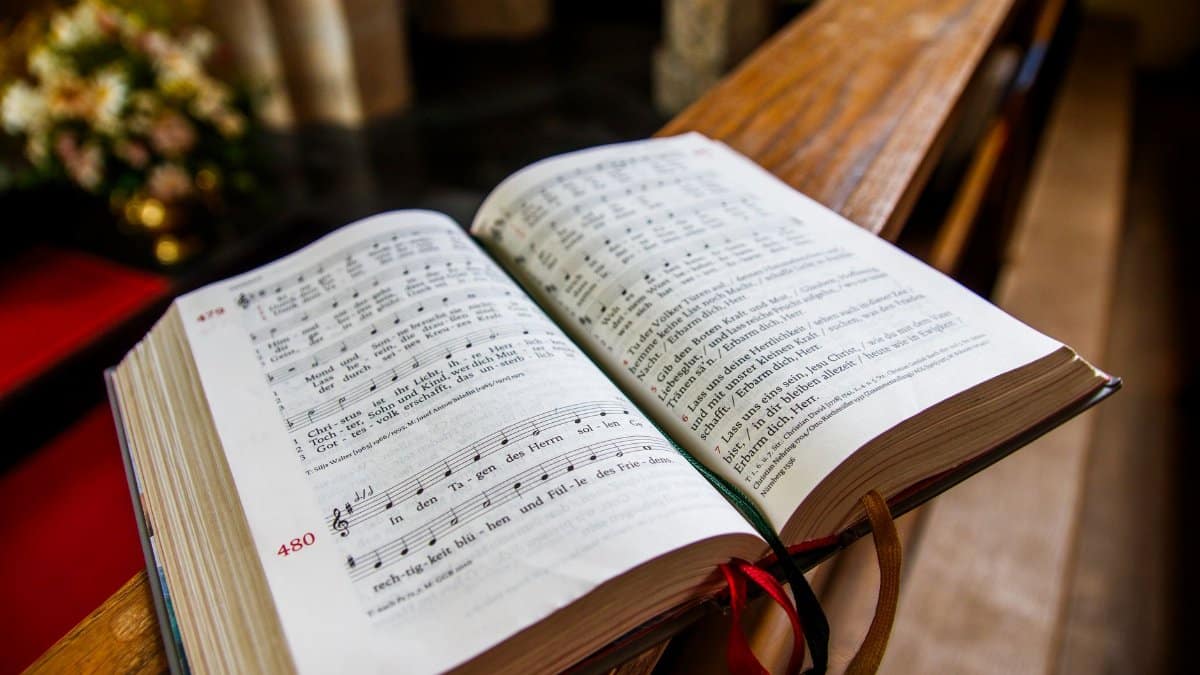 A music hymn book opened on a church pulpit, illuminated by warm indoor lighting.