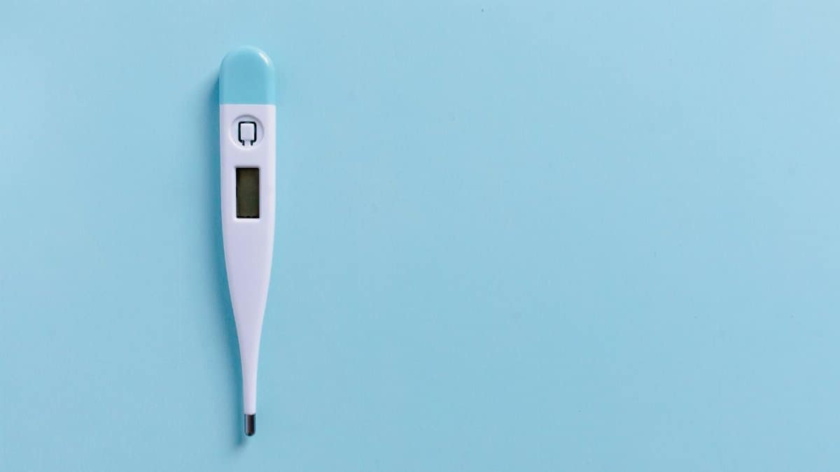 Close-up of a digital thermometer on a light blue background with copyspace.