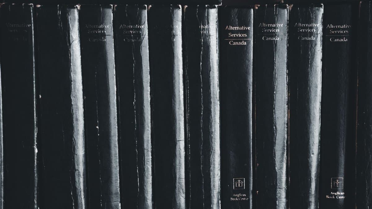 Close-up of black books on a shelf highlighting their titles.