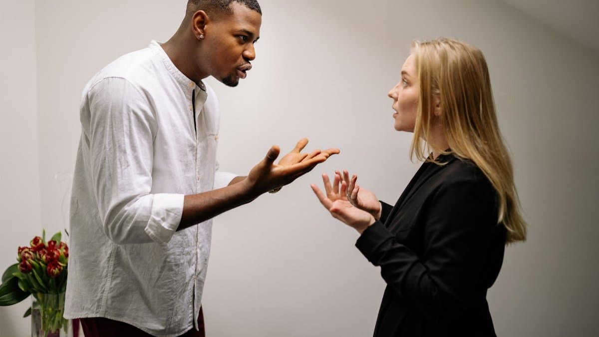 A man and woman engaged in a heated office argument, displaying emotion and intensity.