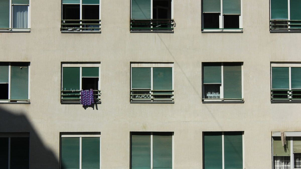 A minimalist view of a modern apartment building facade with repetitive window pattern.