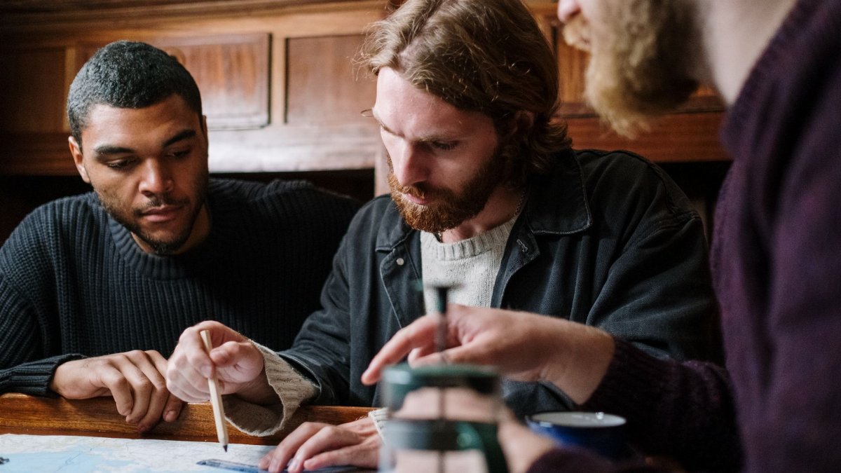 A group of young men engaged in planning a nautical adventure indoors using a detailed map.