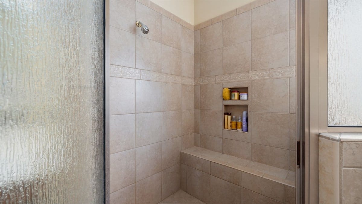 Elegant walk-in shower with beige tiles and built-in shelves, perfect for a modern bathroom.