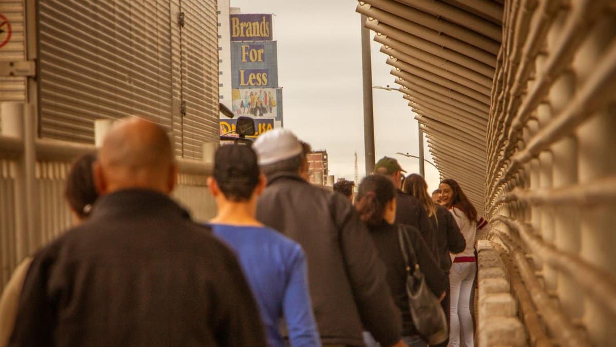 People walking on a busy sidewalk in an urban area of Puerto Iguazú, Brazil. Street scene with diverse crowd.