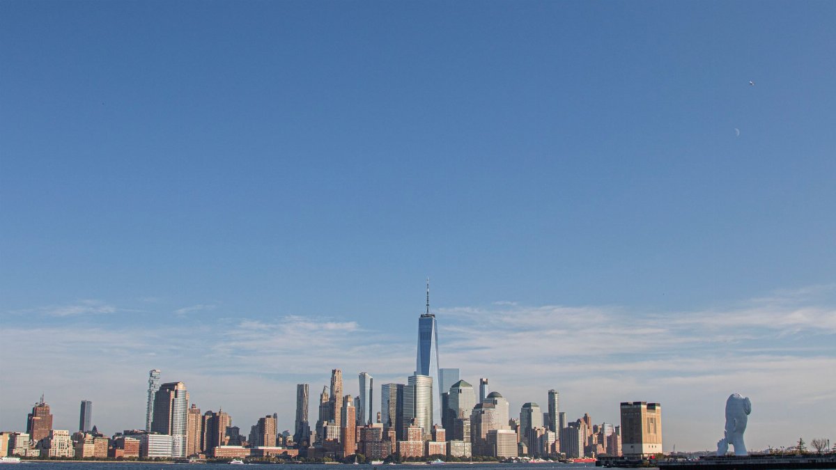 Iconic New York City skyline featuring the One World Trade Center under a clear blue sky.