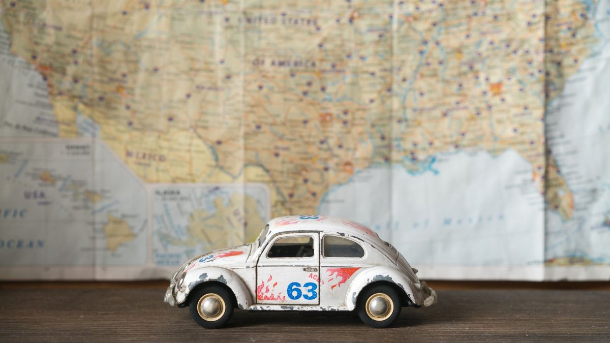 Close-up of a vintage toy car model with map background, symbolizing travel and exploration.