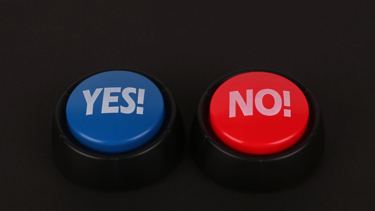 Side-by-side colorful yes and no push buttons on a dark surface symbolize decision making and choices.