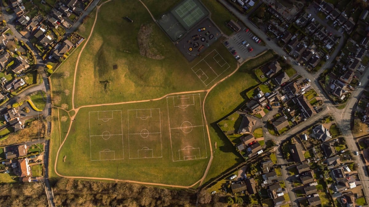 Aerial photo showcasing soccer fields and a suburban neighborhood in bright sunlight.