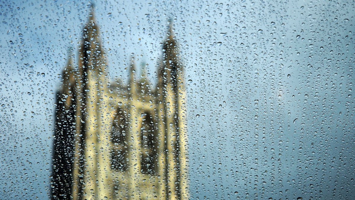 View of a blurred cathedral tower seen through rain-soaked glass, creating a textured effect.