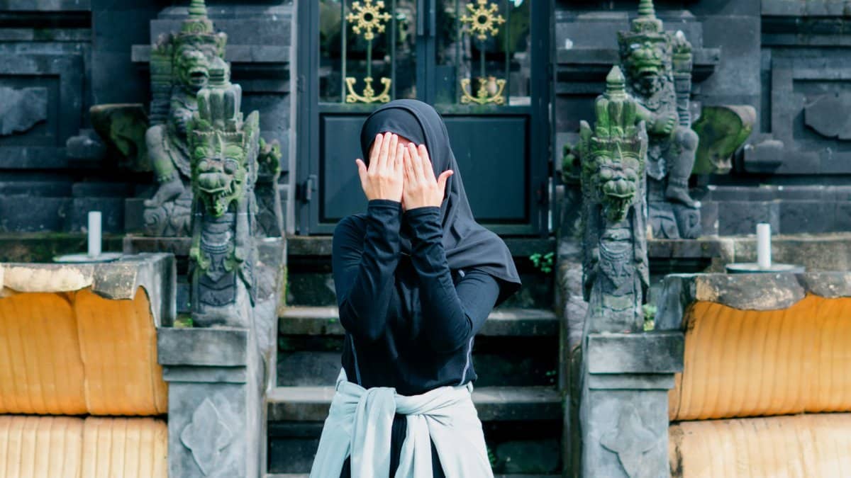 A woman in a black outfit poses mysteriously at a traditional temple in Banten, Indonesia.