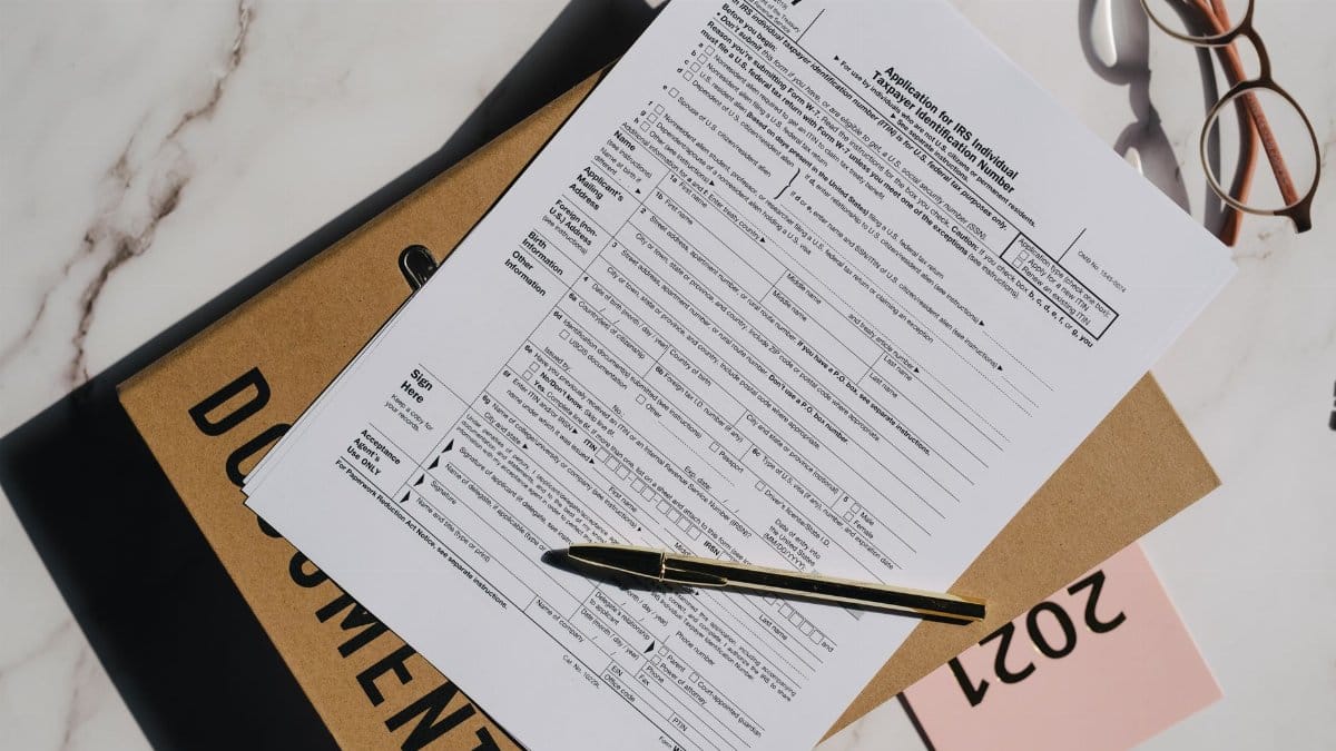Top view of a tax form with a pen and eyeglasses on a marble surface, perfect for finance themes.