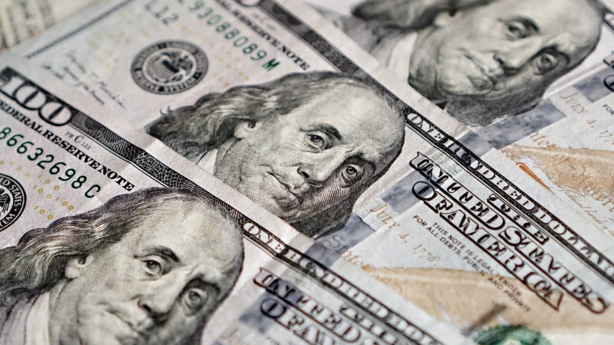 Detailed view of multiple US hundred dollar bills featuring Benjamin Franklin.