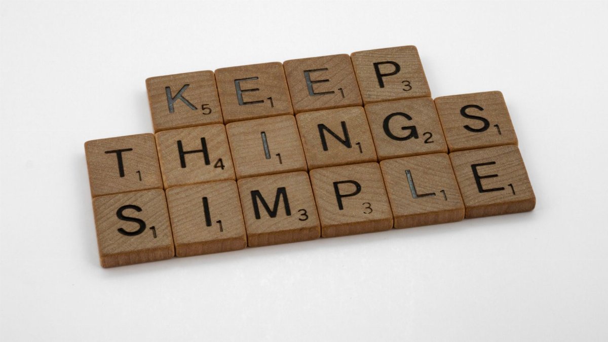 Motivational phrase 'Keep Things Simple' spelled out with wooden Scrabble tiles on a white background.