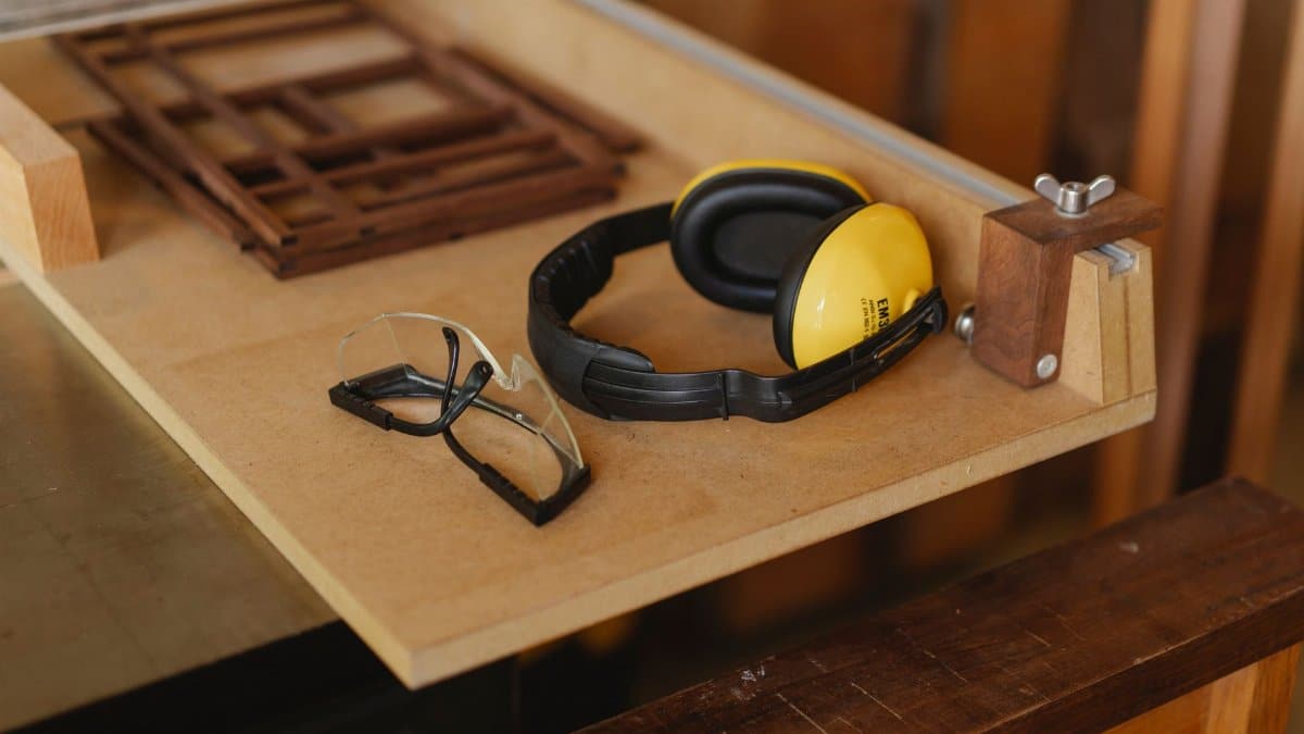 From above of noise cancelling headphones with protective glasses for joinery on wooden table in workroom