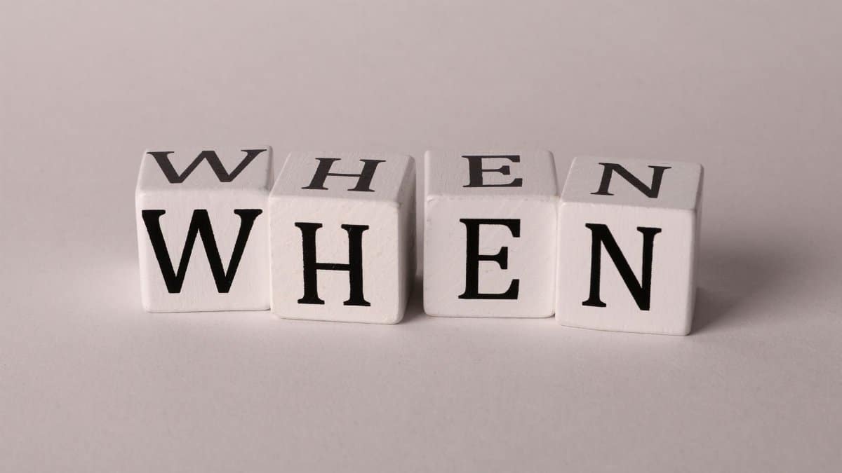Minimalist photo of wooden blocks with the word 'WHEN' on a white background.