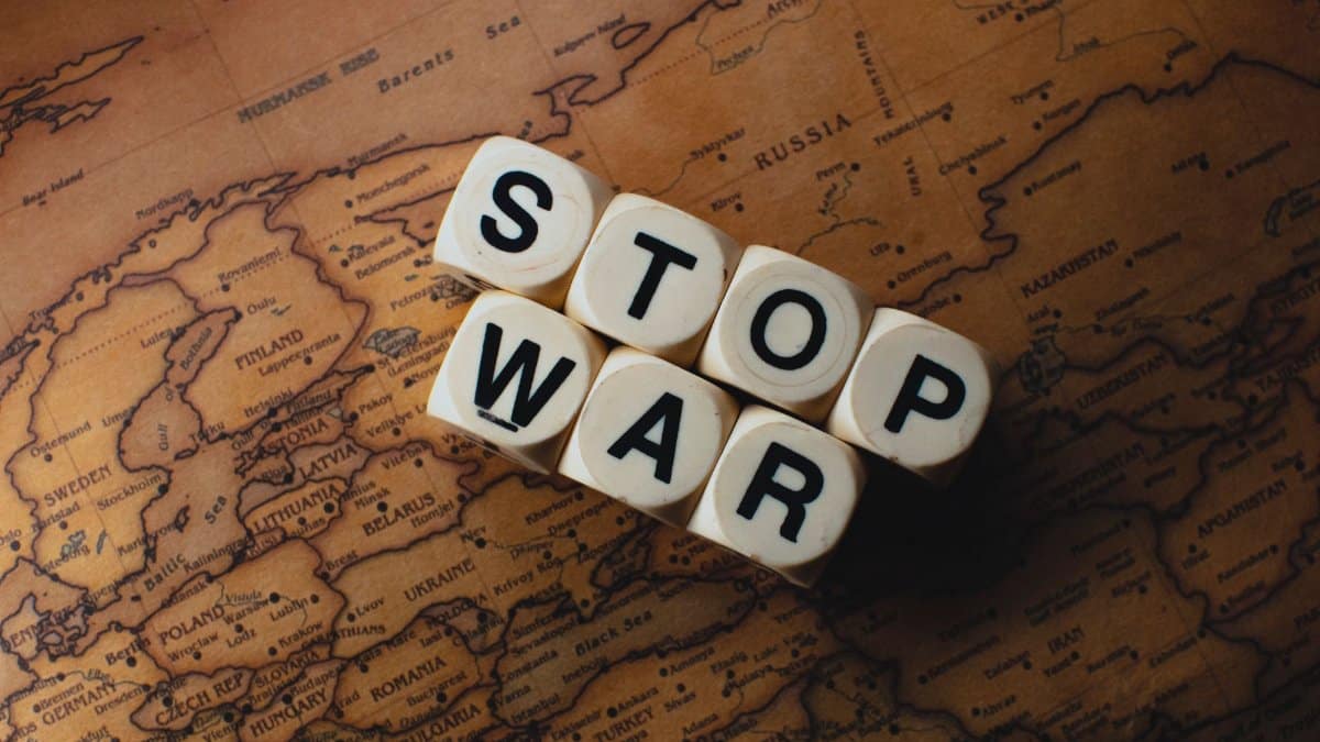 Dice with 'STOP WAR' on a vintage world map signifies peace.