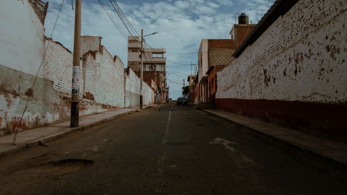 Explore a deserted street lined with rustic buildings in Pacasmayo, Peru, under a blue sky.