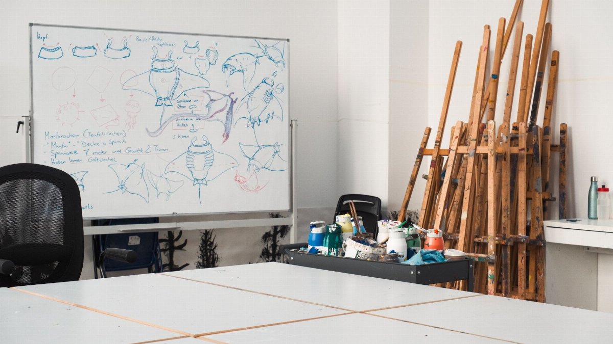 Creative art studio featuring sketches on a whiteboard and easels against the wall.