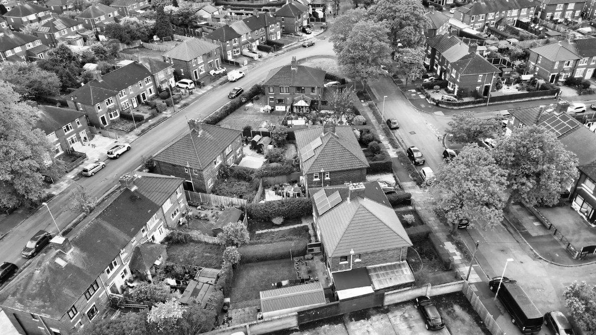 Aerial view of a suburban neighborhood in black and white, showcasing residential houses and streets.