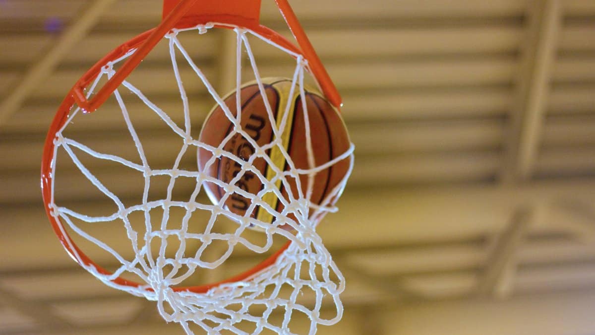 Close-up of a basketball successfully passing through a hoop indoors.
