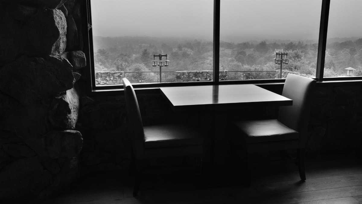 Black and white interior view featuring a table for two with window overlooking Asheville.