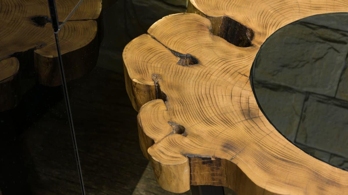 From above of wooden table with curved lines and spots on surface reflecting on glass wall