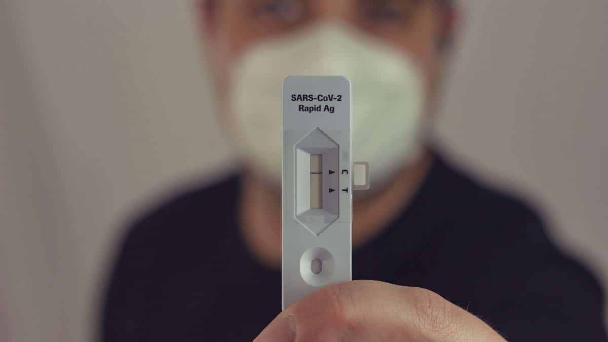 A person holding a negative COVID-19 antigen test with a face mask on, focused on the test result.