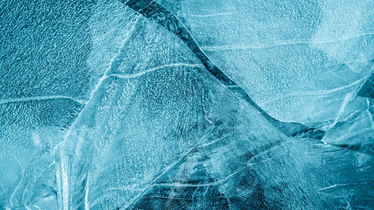 From above of frozen crystal water with thin uneven pieces of ice with cracks in daytime