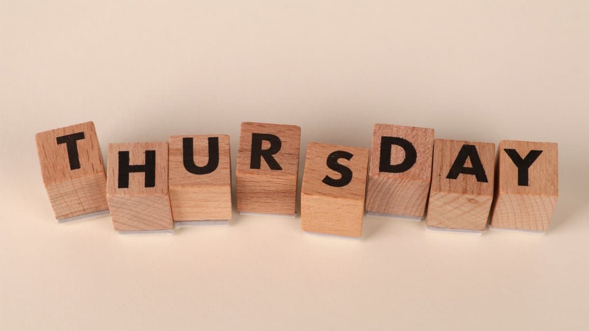 Wooden blocks arranged to spell Thursday on a neutral background.