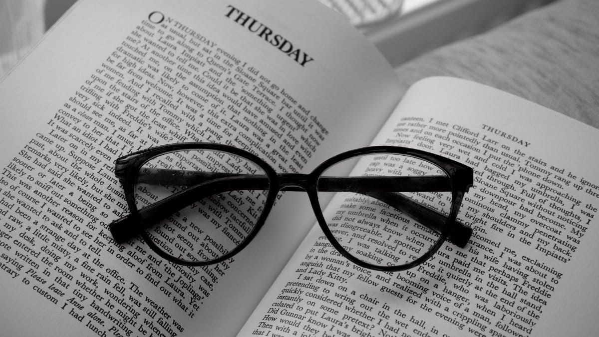 Black stylish glasses resting on an open book displaying the word 'Thursday'. Perfect for reading themes.