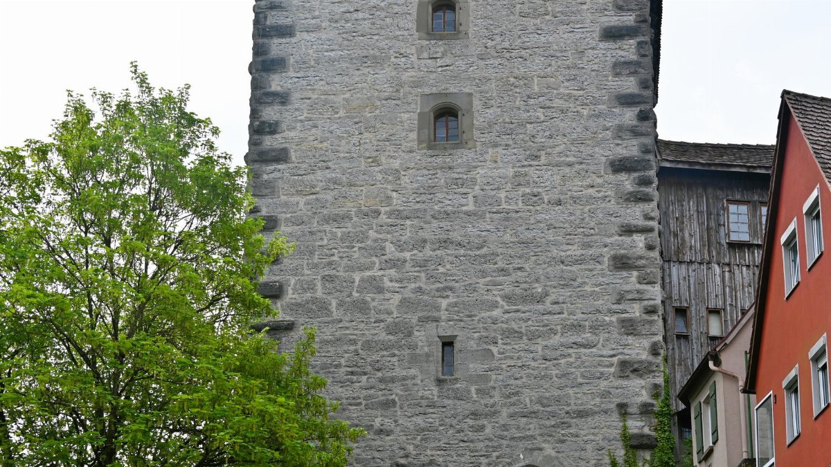 A majestic stone tower set among medieval architecture and trees in Germany.
