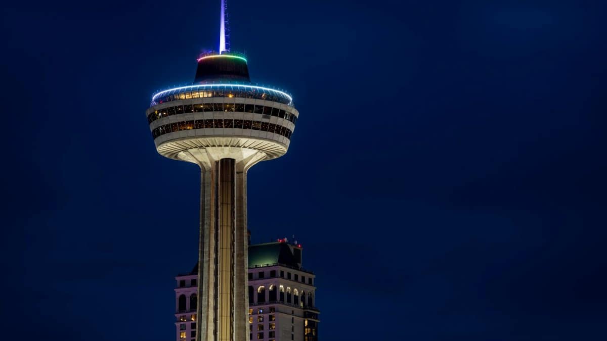 View of Skylon Tower in Niagara Falls beautifully lit against a dark night sky.