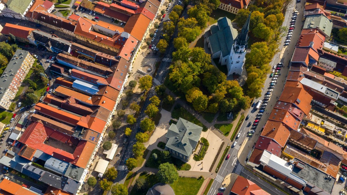 A stunning aerial shot of a historic European town center with a church and vibrant red rooftops.