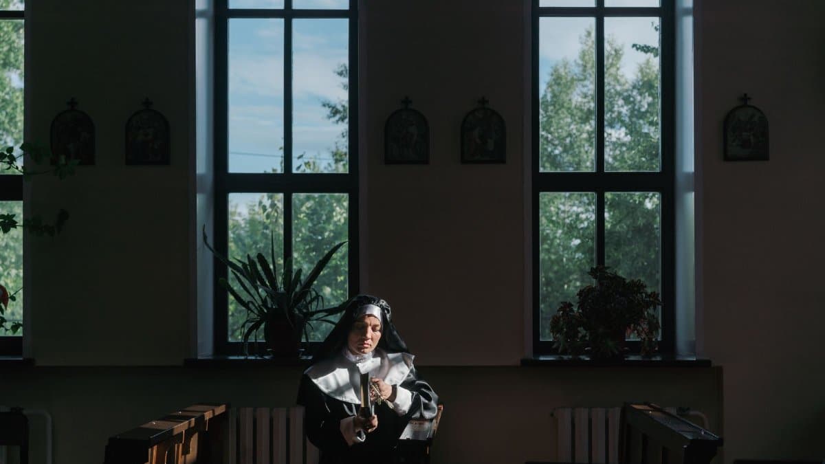 Nun in a tranquil church setting, reading and reflecting in afternoon light.