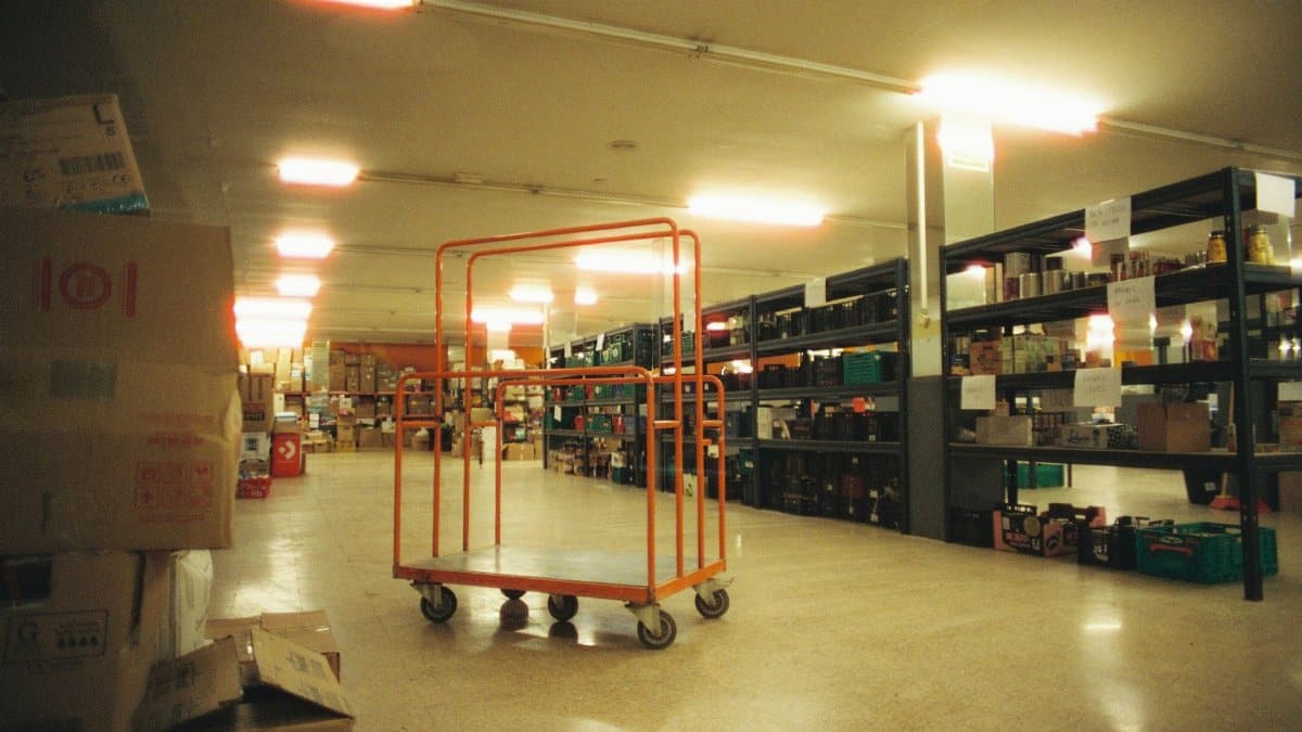 Industrial warehouse interior featuring shelves and an orange cart, ideal for logistics.