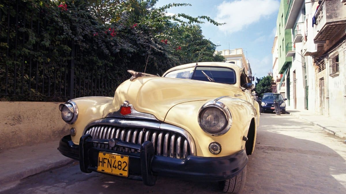 A classic yellow car parked on a sunny street in Havana, Cuba featuring vibrant colors and retro charm.