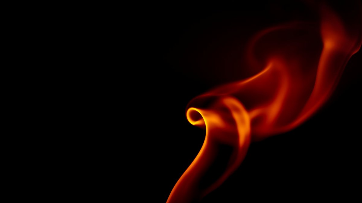Close-up of a swirling flame against a dark backdrop, capturing movement and heat.