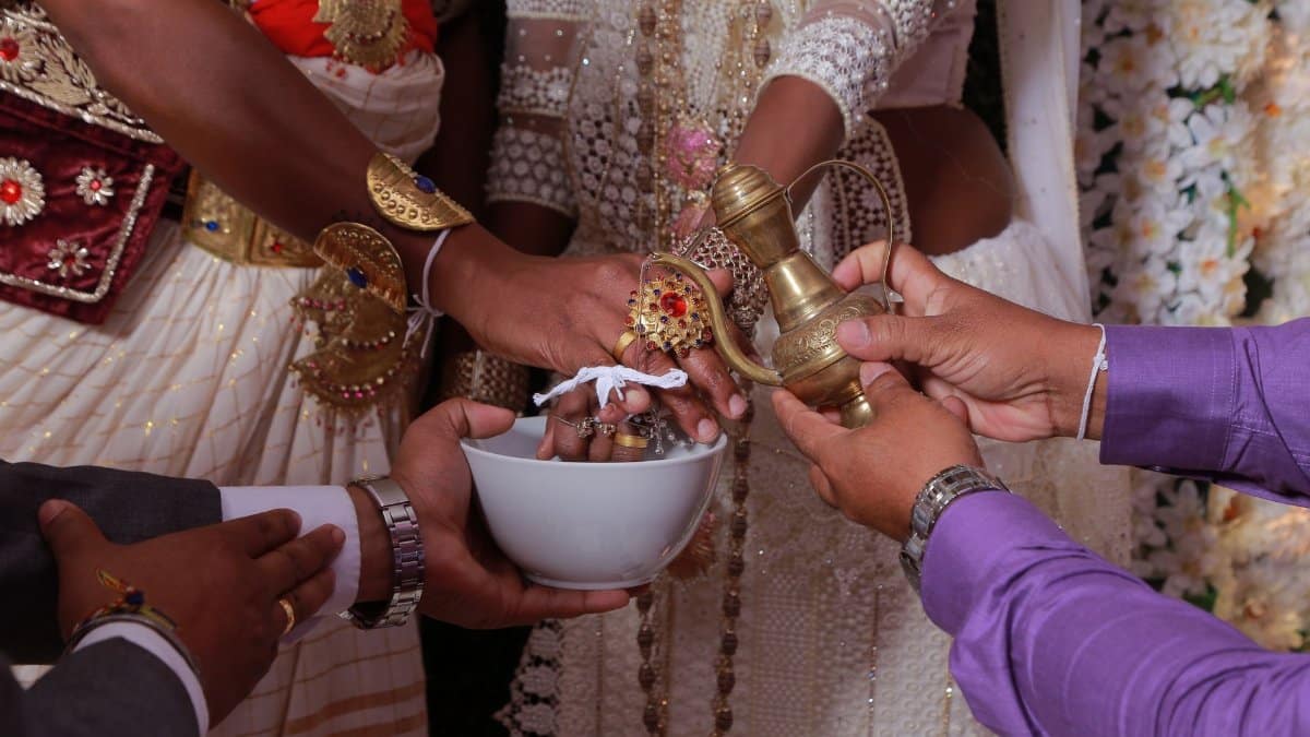 Close-up of a traditional Sri Lankan wedding ceremony where water is poured on hands, symbolizing unity and blessings.