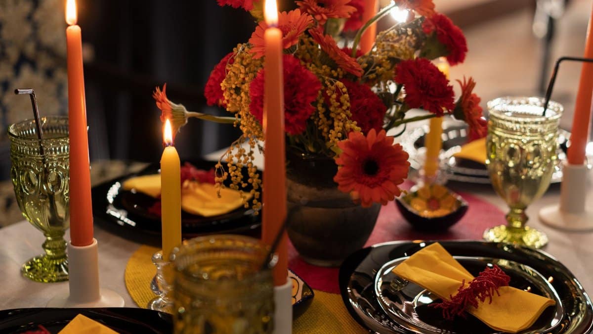Stylish dining table with candles, vibrant flowers, and elegant glassware.