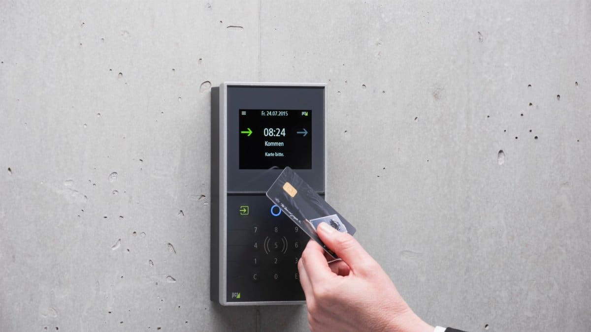 A businessman uses a secure card reader access system against a concrete wall.
