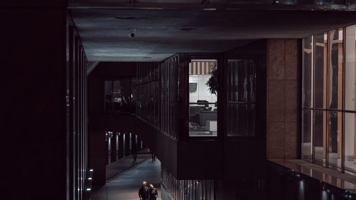 People walking in a modern architectural alley at night in London, England.