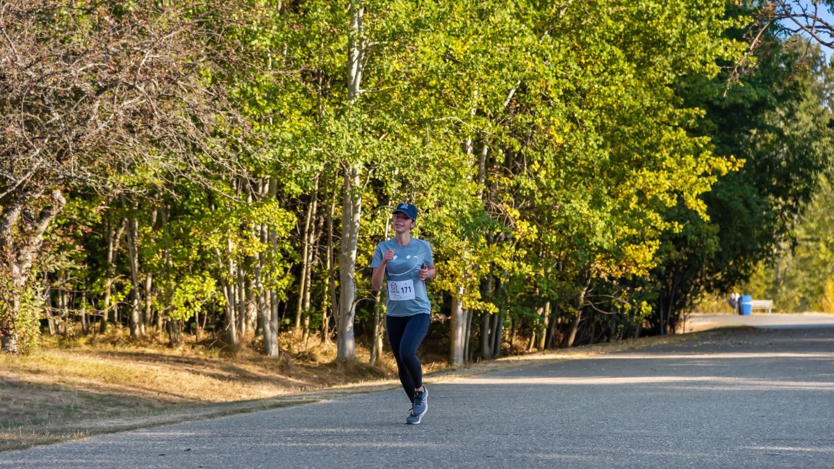 Woman enjoying a fall marathon run on a scenic tree-lined road.