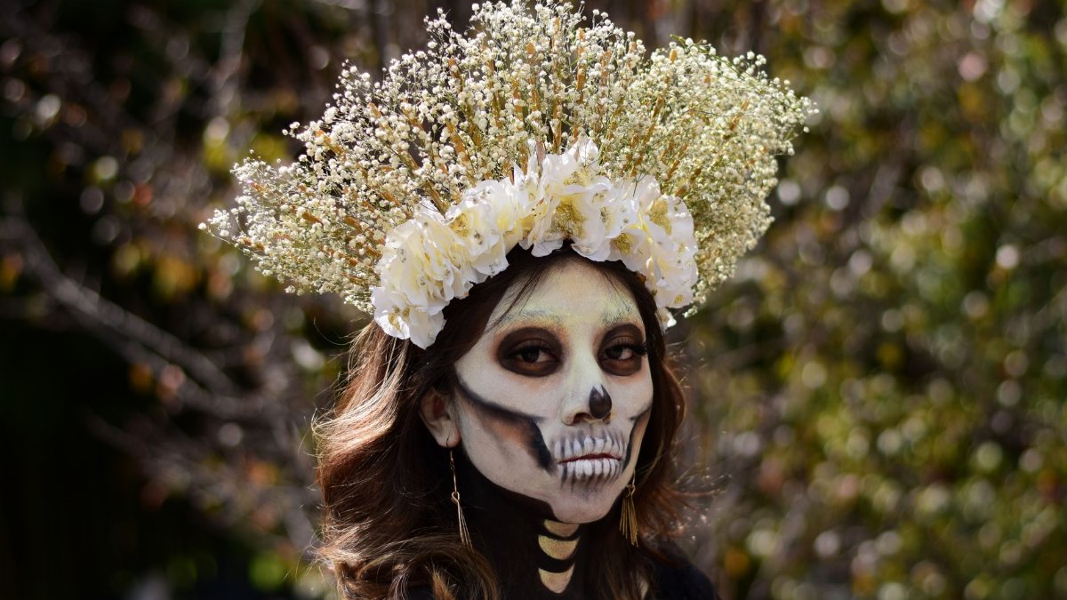 Woman with skeletal makeup and a floral crown, Day of the Dead celebration.