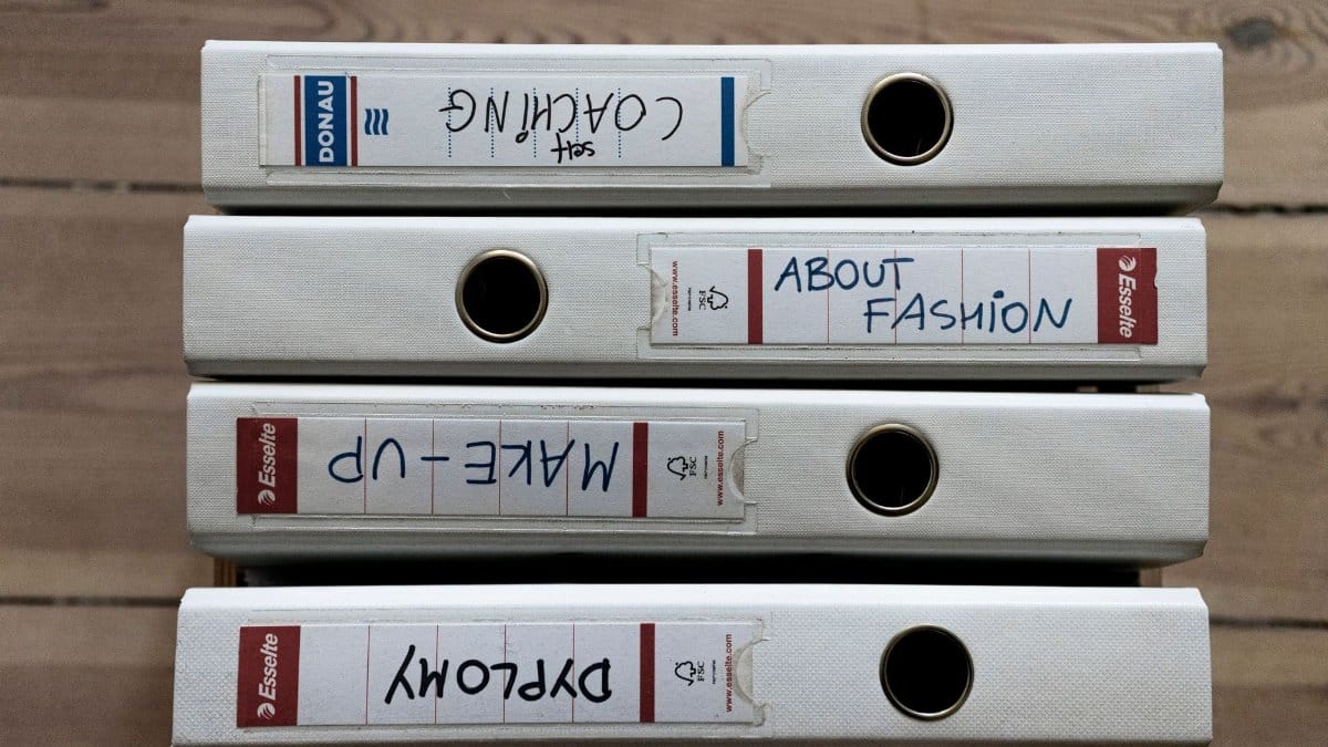 From above of collection of ring binders with stickers and written titles on wooden parquet