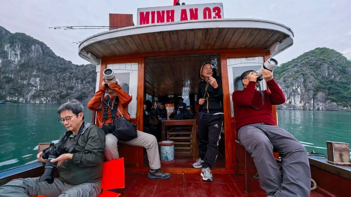 Photographers on a boat capturing the stunning landscapes of Halong Bay.