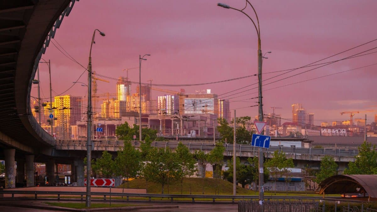 Stunning Kyiv skyline at sunset, showcasing a bridge and city buildings under a dramatic sky.