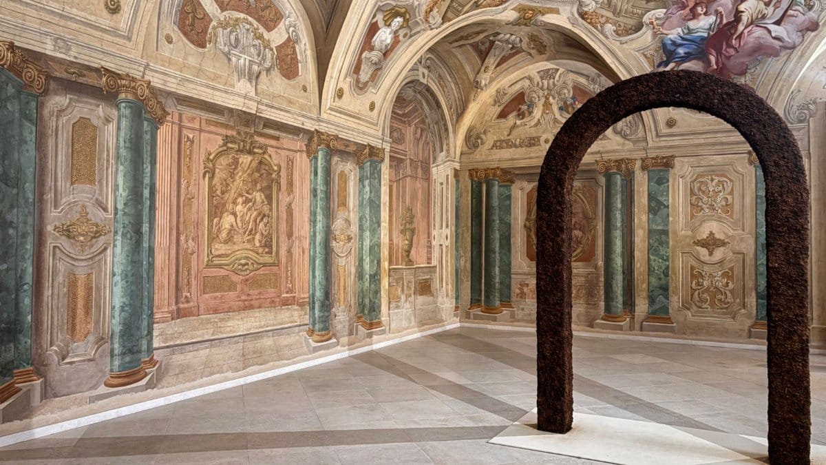 Elegant Baroque room featuring detailed frescoes and a modern arched sculpture.