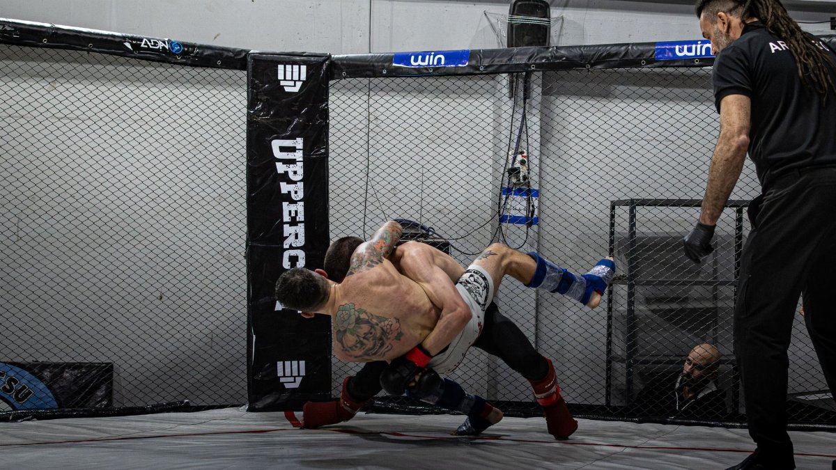 Two MMA fighters battling in a cage during a match in Buenos Aires.