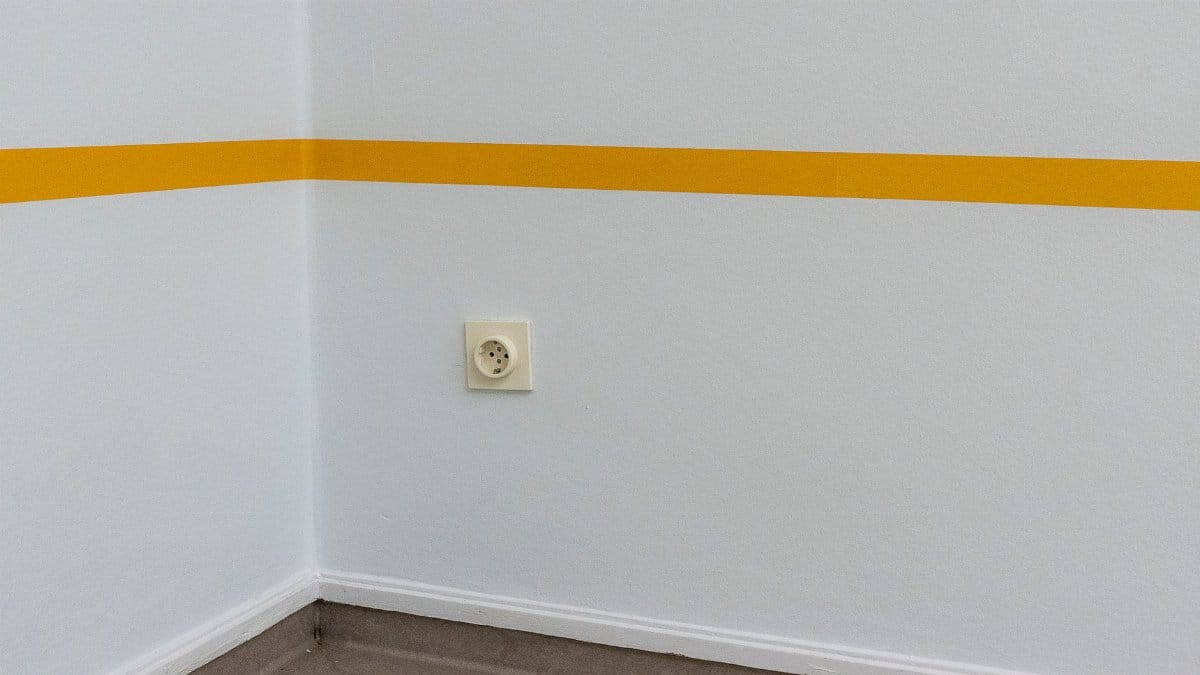 A clean wall with a yellow stripe and an electrical socket adds modern minimalist style.