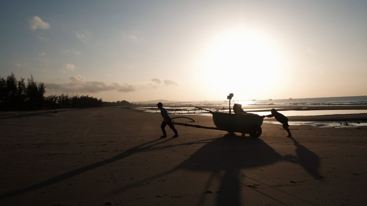 Fishermen on Phan Thiet beach at sunrise, showcasing hard work and stunning scenery.